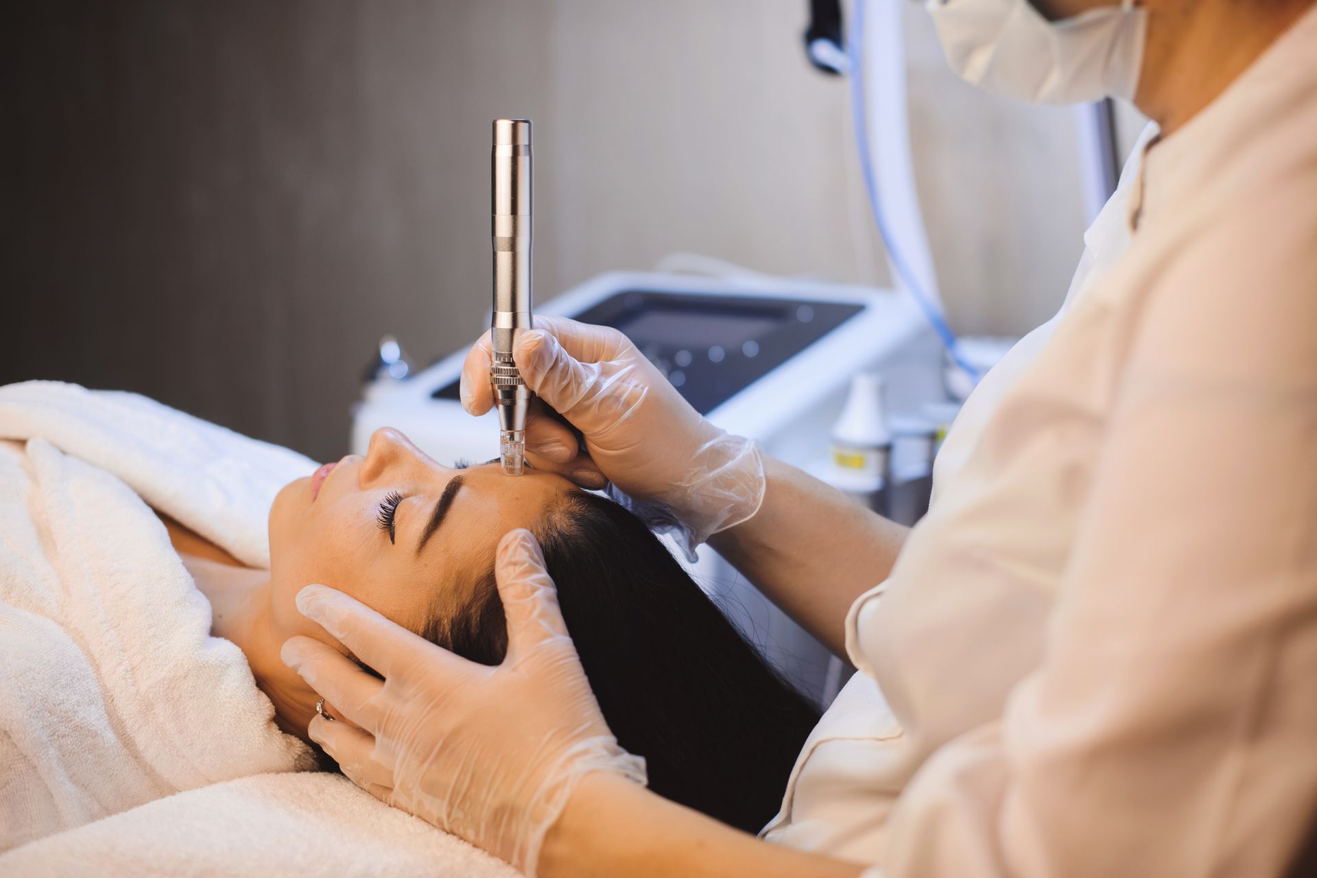 Person receiving facial treatment with a handheld device, in a spa setting.