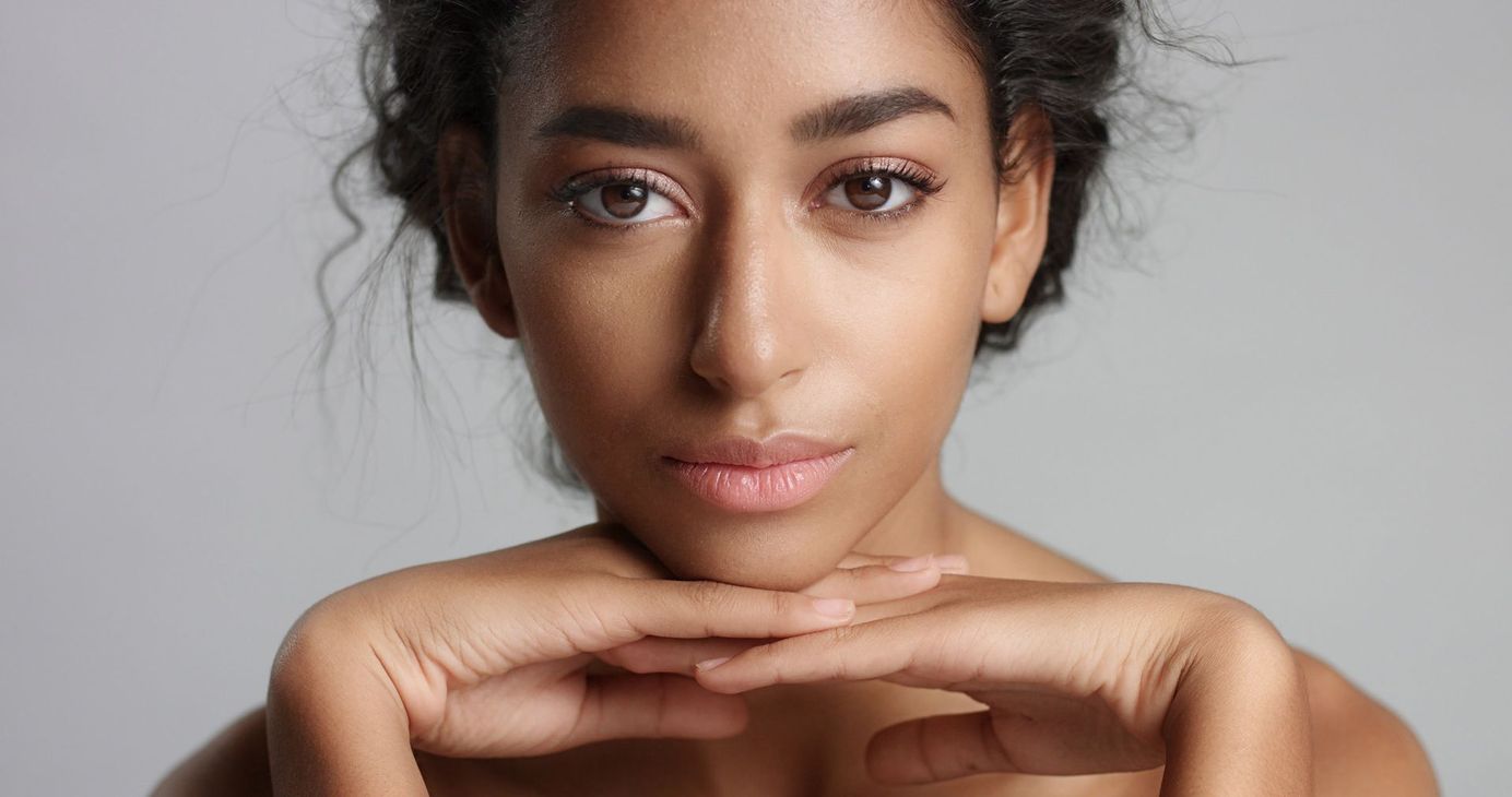 A close up of a woman 's face with her hands on her chin.