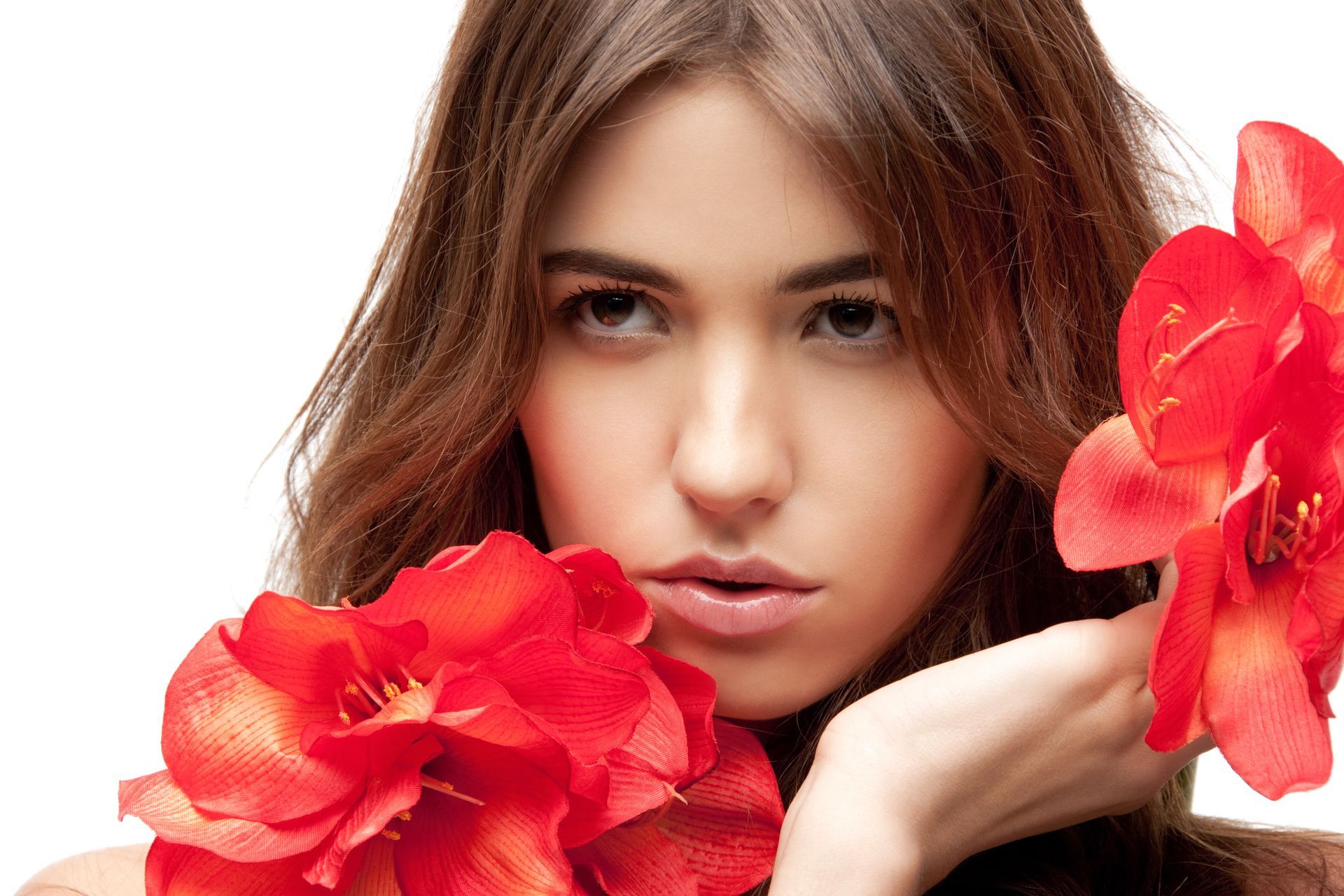 A woman is holding red flowers in front of her face.