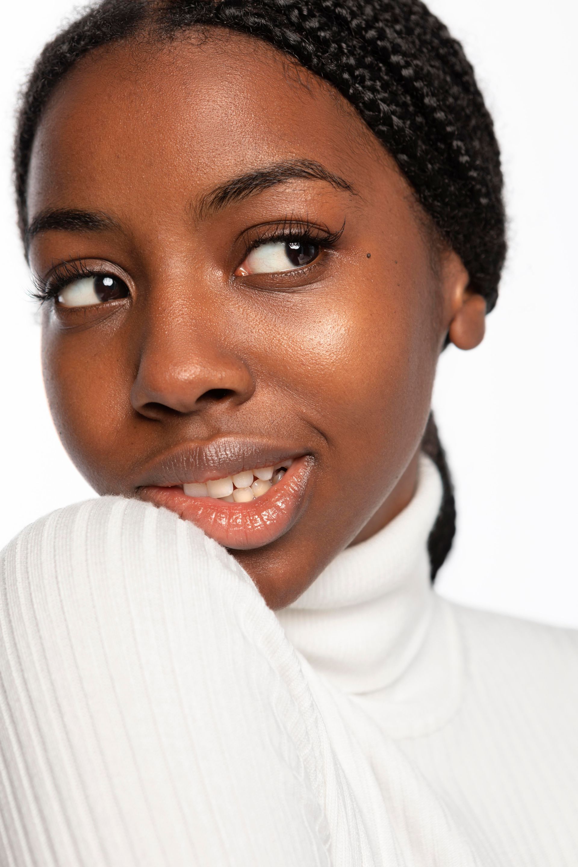A beautiful young woman is holding her hands to her face.