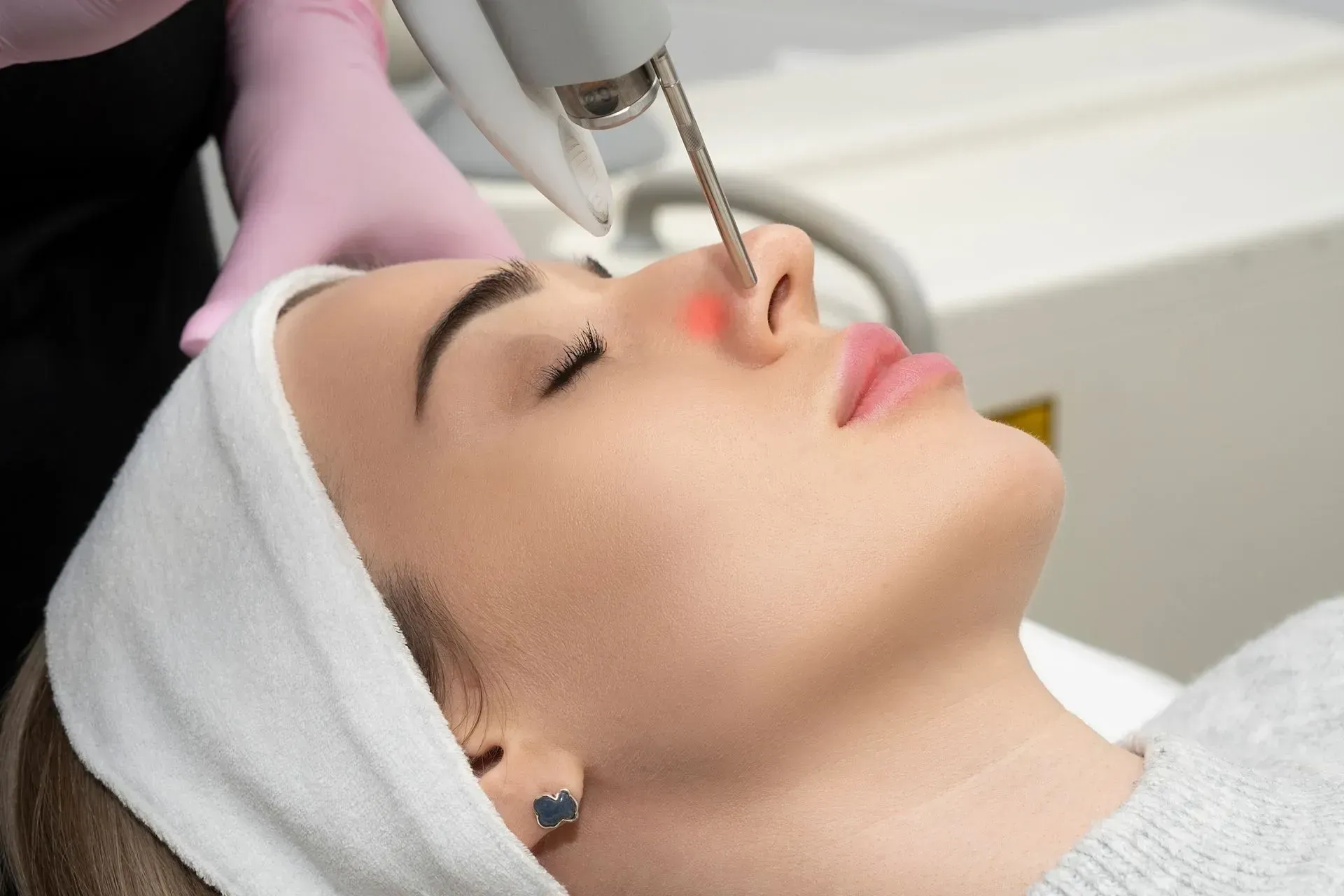 A woman is getting a laser treatment on her nose.