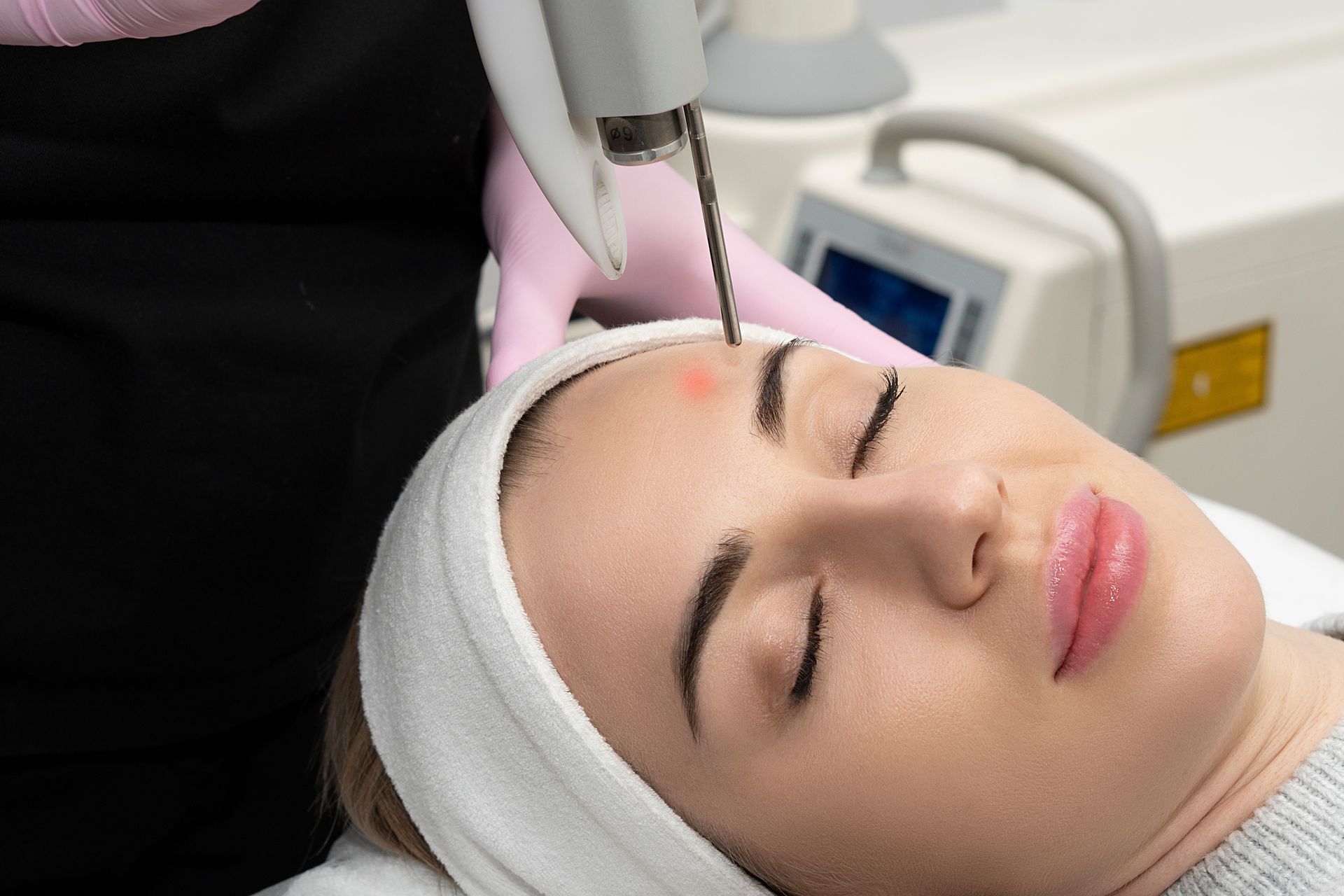 A woman is getting a laser treatment on her forehead.