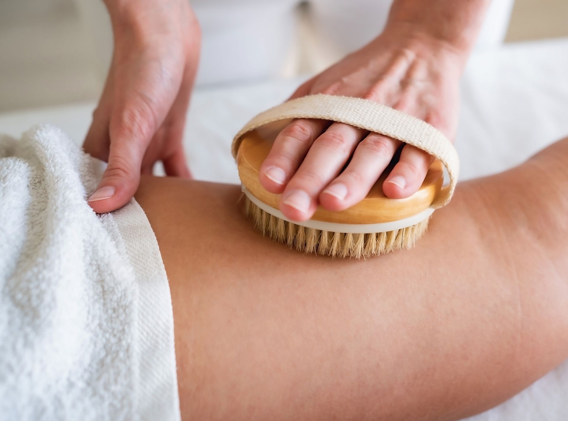 A woman is getting a massage with a brush on her leg.