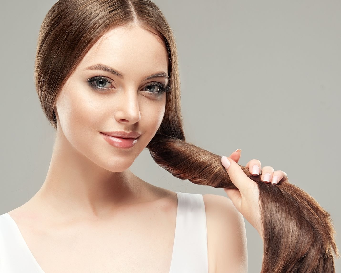 A woman is holding her hair in her hand and smiling.