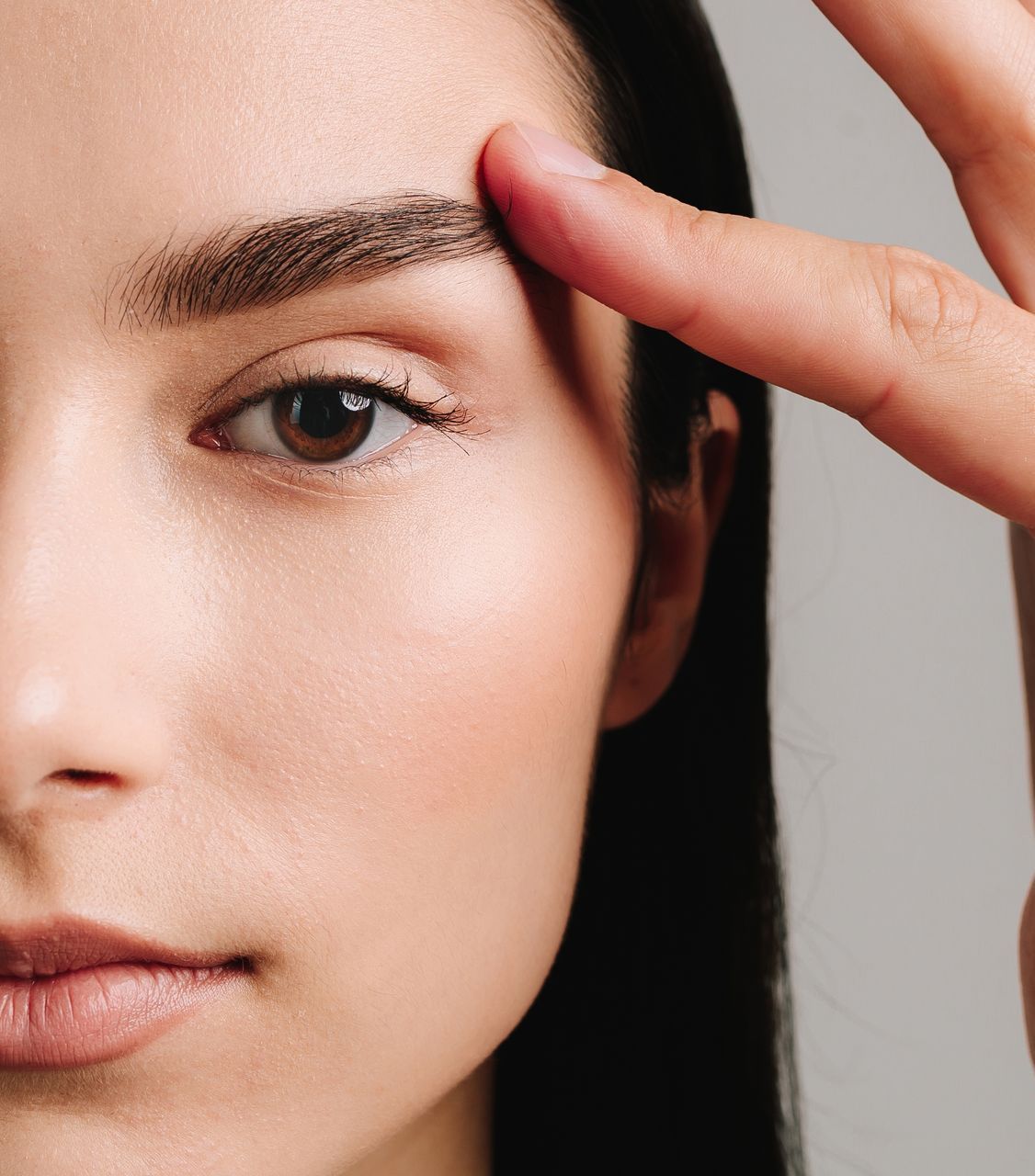 A woman is touching her eyebrows with her finger