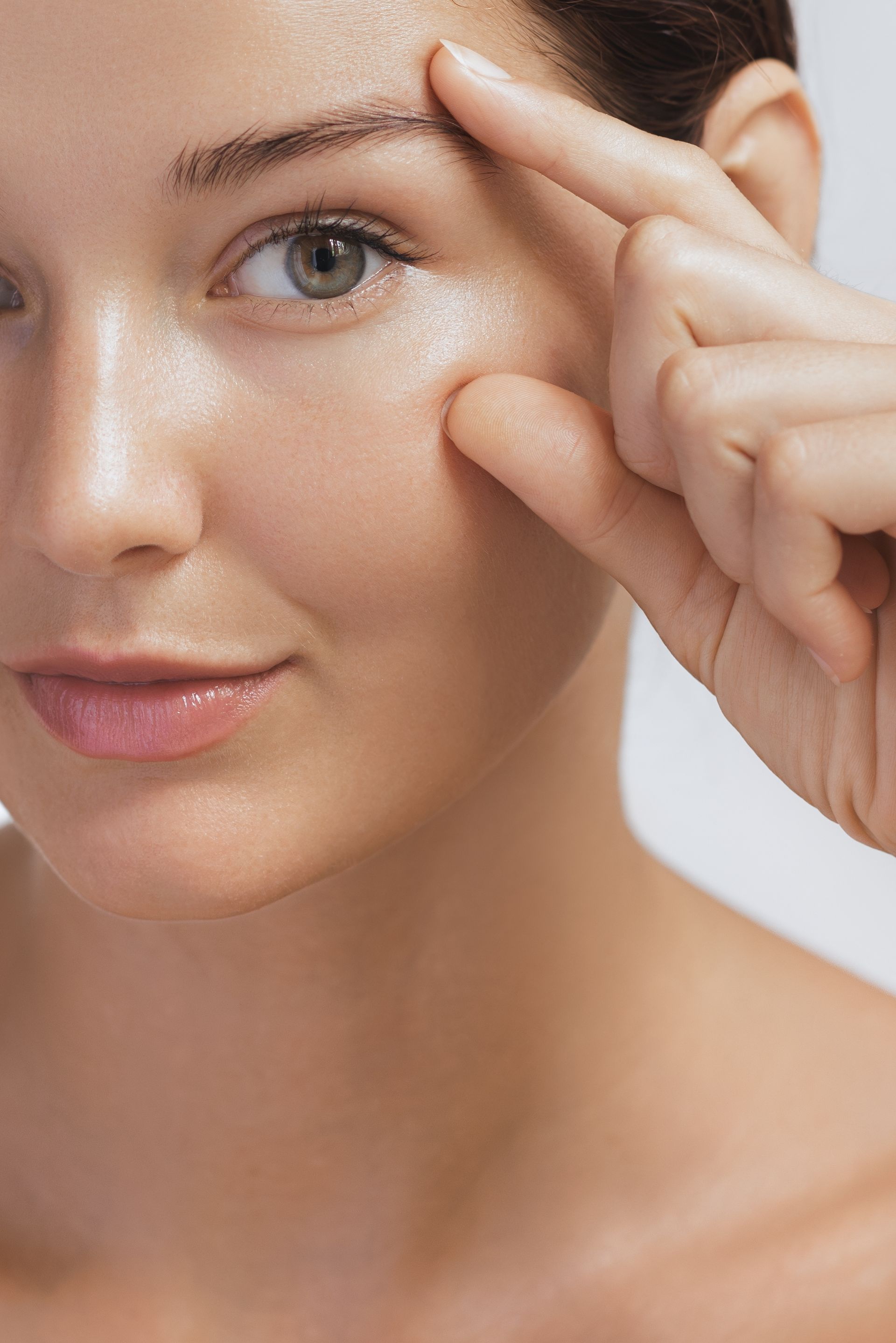 A woman is touching her eyebrow with her finger.