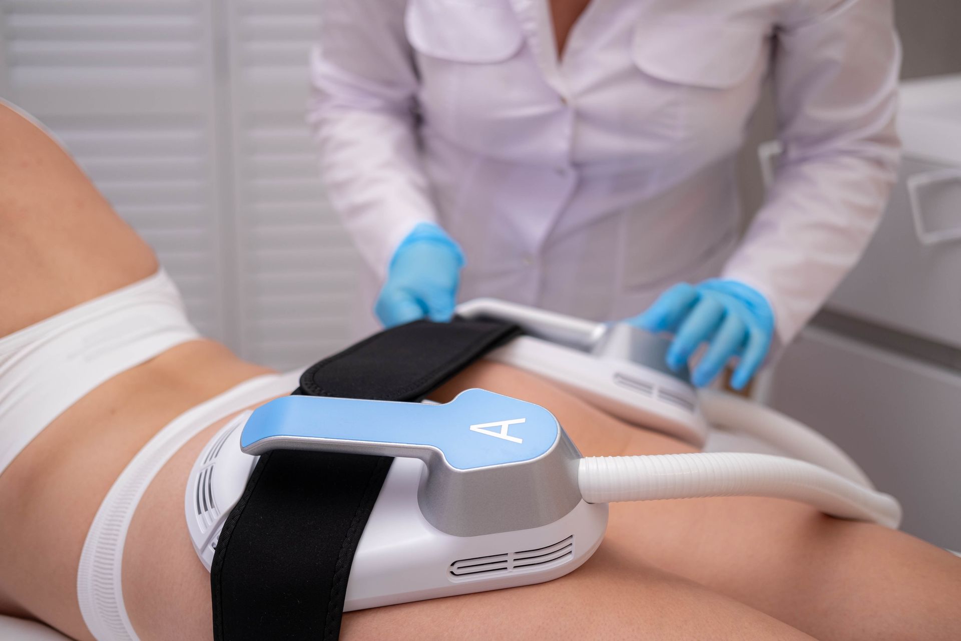 A woman is laying on a bed getting a massage from a doctor.
