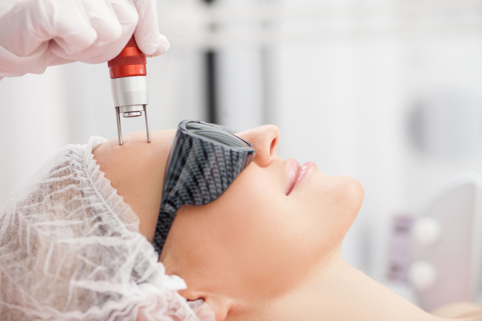 A woman is getting a laser treatment on her face.