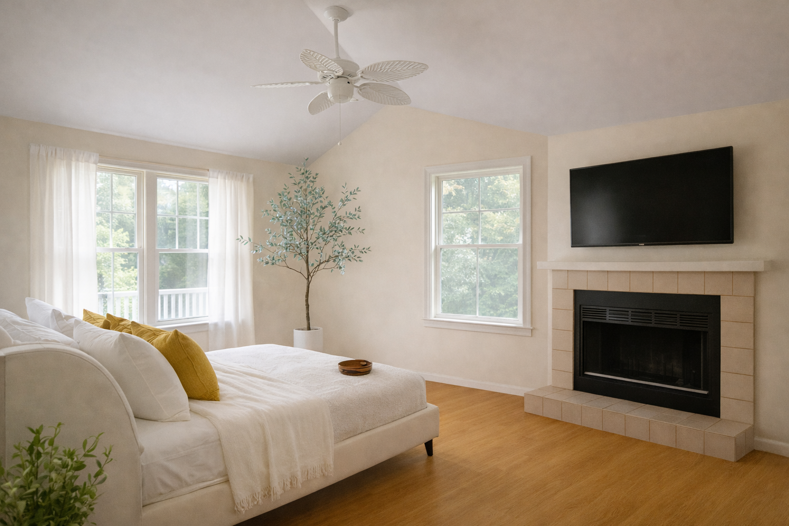 Bedroom with white walls, bed, fireplace, TV, windows, and light wood floors.