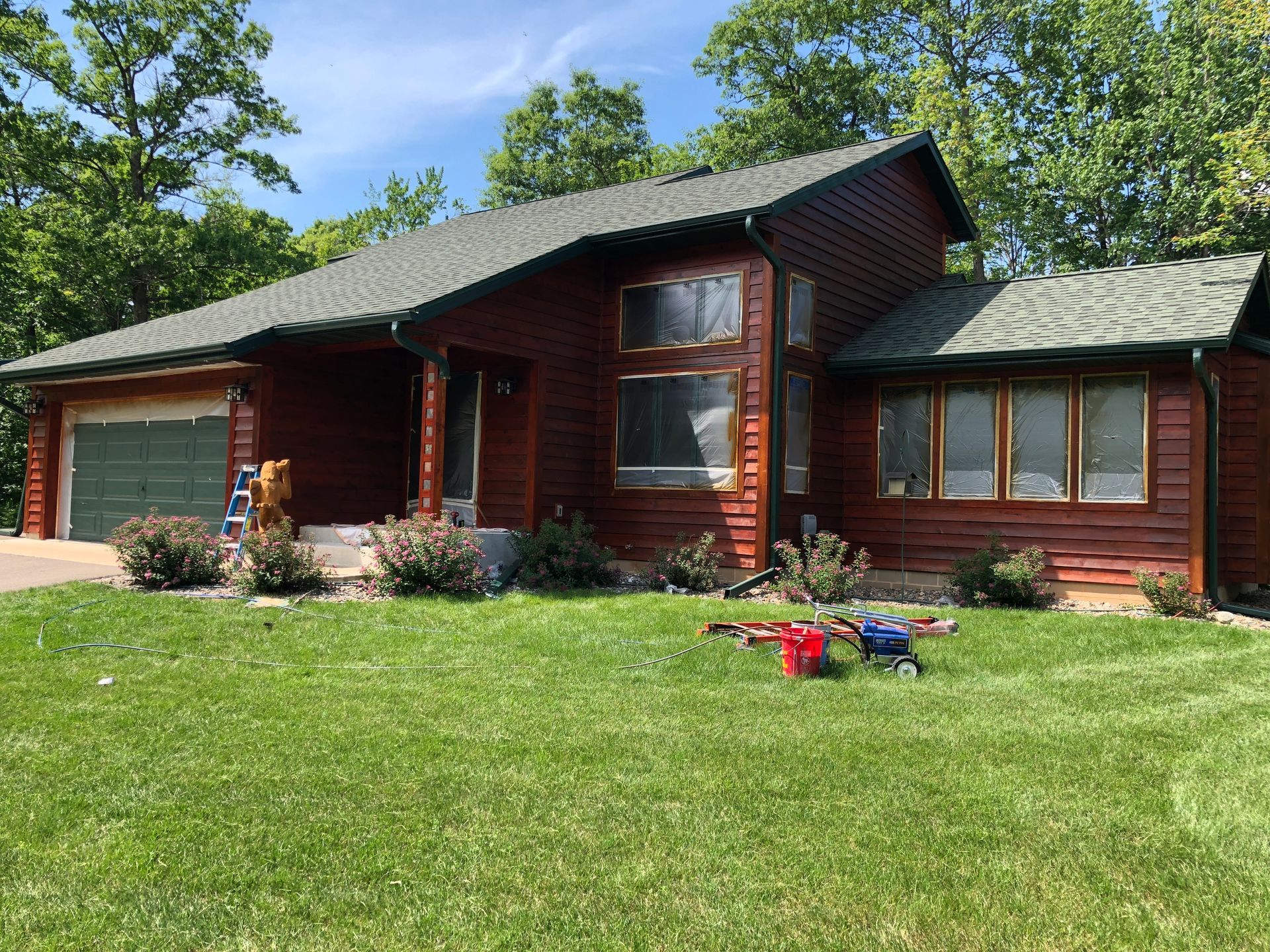 A Wooden House With a Lawn in Front – MN - Lifetime Staining and Log Restoration