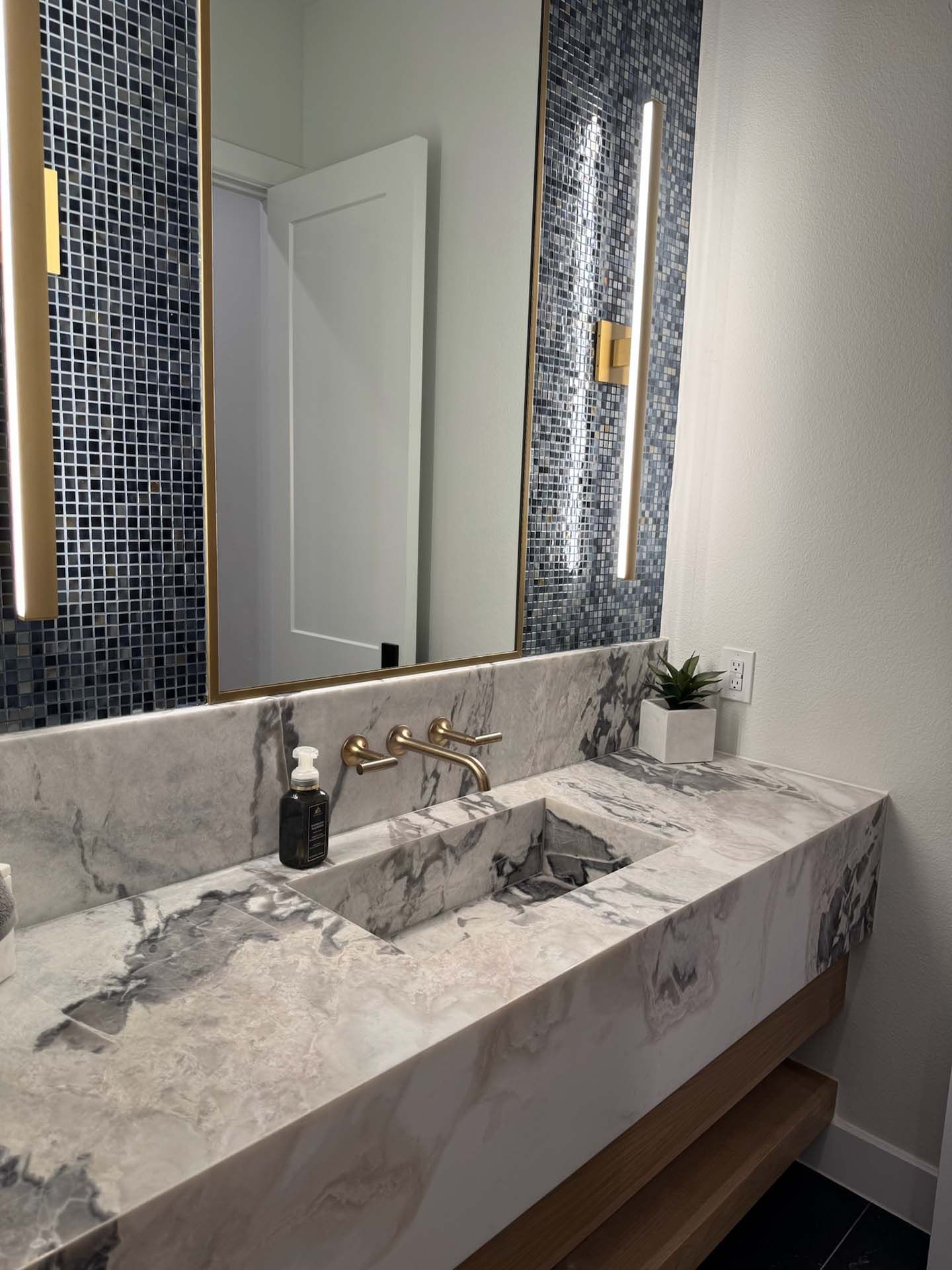 A bathroom with a sink, mirror, and marble countertop