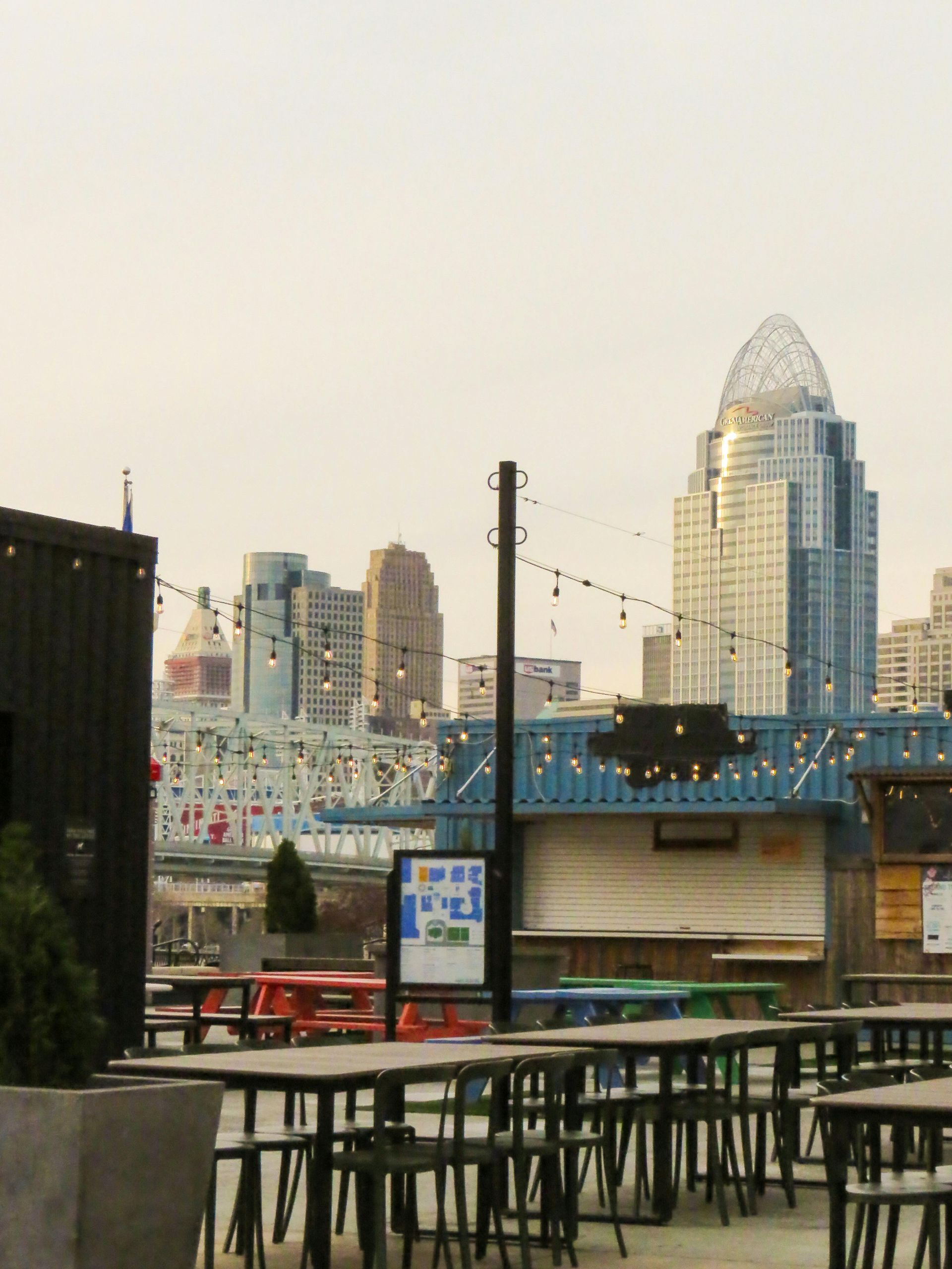An outdoor patio with tables and chairs featuring a view of the Cincinnati skyline, including the Great American Tower.