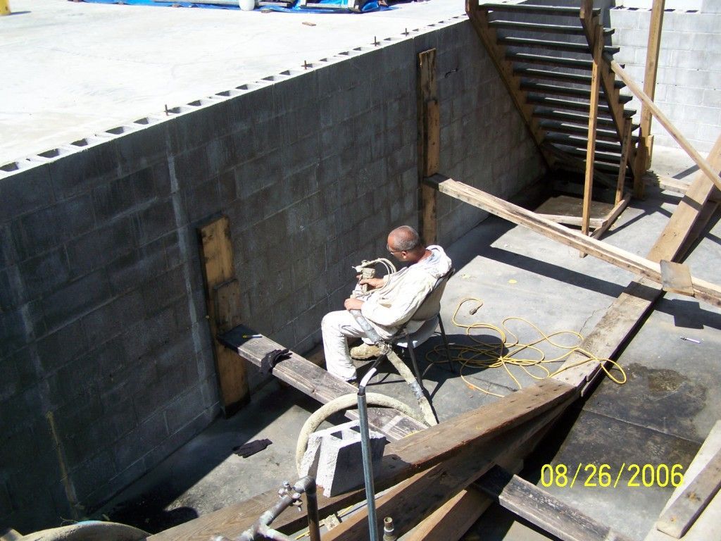 A man is sitting in a chair in front of a brick wall with a date of 08/26/2006