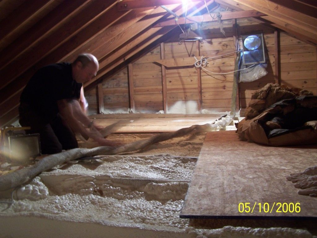 A man is working in an attic with a hose.