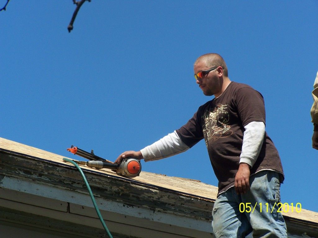 A man with spray insulation from a hose on a roof