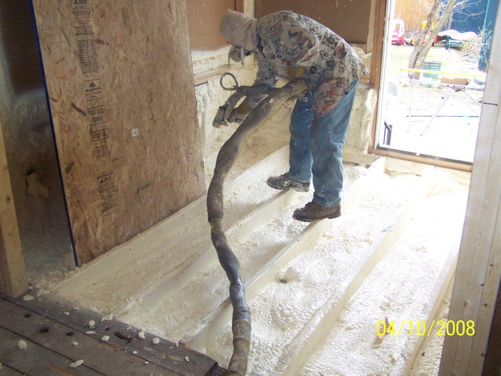 A man is blowing insulation into a wooden floor.