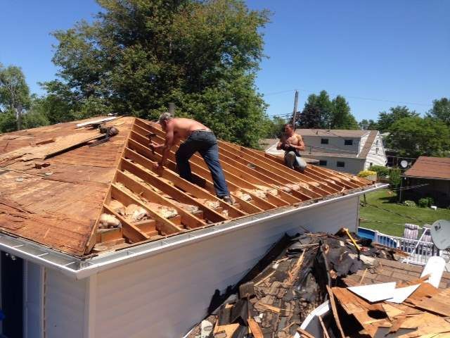 Two men are working on the roof of a house