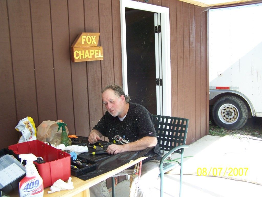 A man sits at a table in front of a sign that says fox chapel