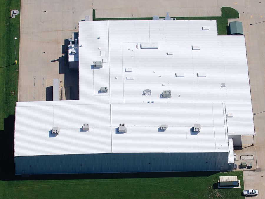 An aerial view of a large building with a white roof