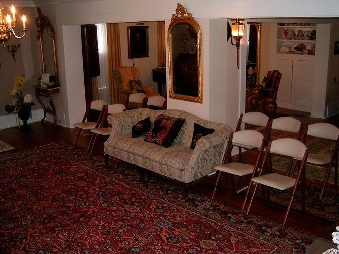 Living room with patterned rug, couch, chairs, and ornate mirrors.