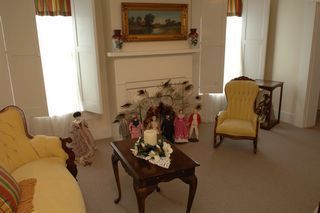 Living room with antique furniture, dolls, and a fireplace.