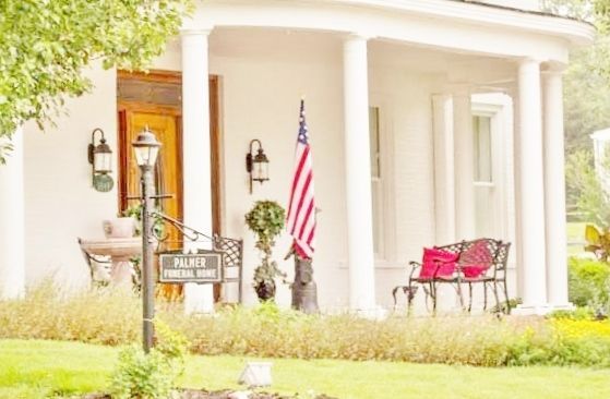 White funeral home with columns, an American flag, and a sign.