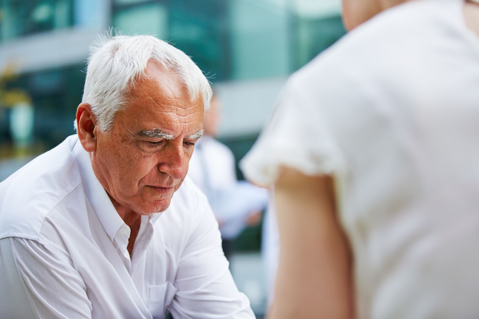 A senior man looking down as he reads a document given to him by a lawyer.