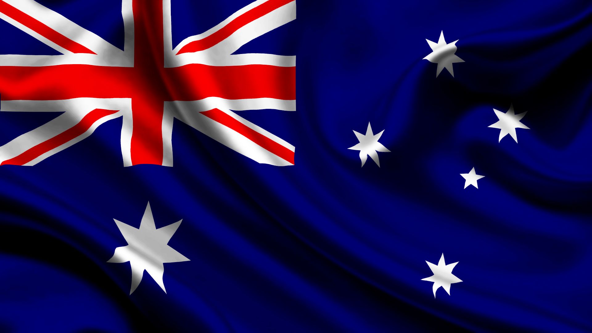 Australian flag waving, with Union Jack in upper left and stars on a white field.