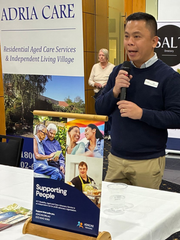 Man speaking into a microphone at a table with an 