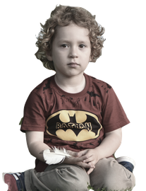 Boy with curly hair wearing a Batman shirt, sitting with a feather.