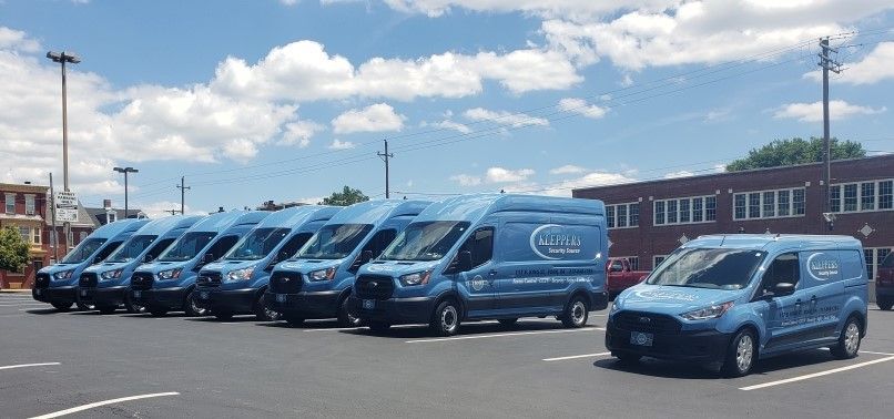 A row of blue vans are parked in a parking lot.