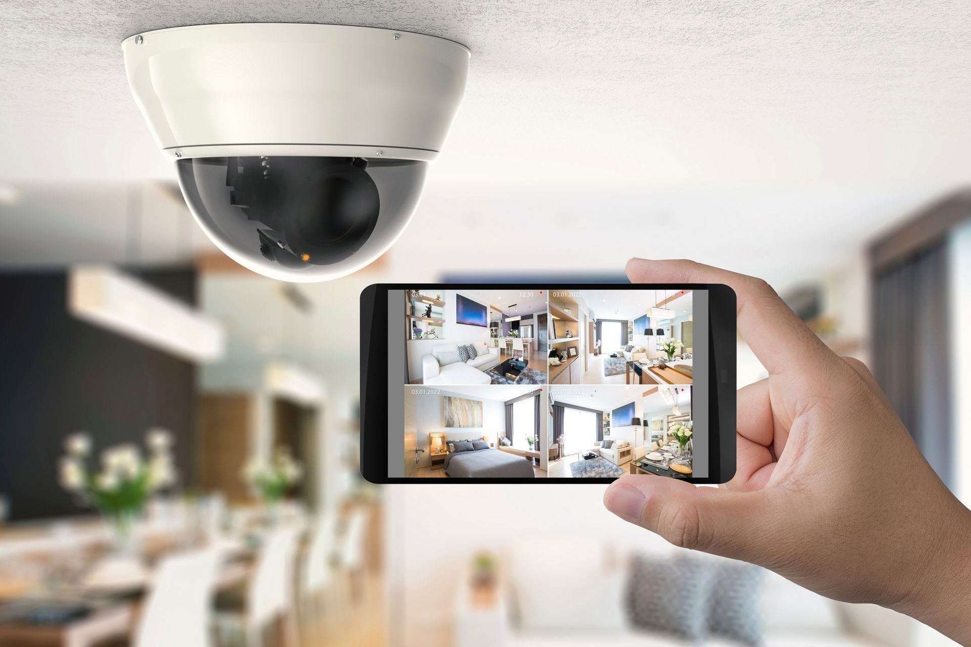 A hand holding a smartphone displaying a security camera app.