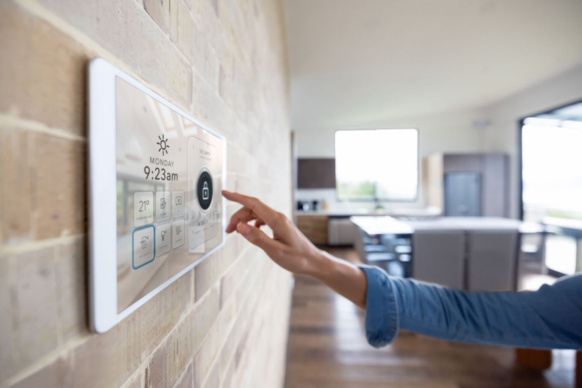 A female hand adjusting home settings on a smart wall-mounted control panel.