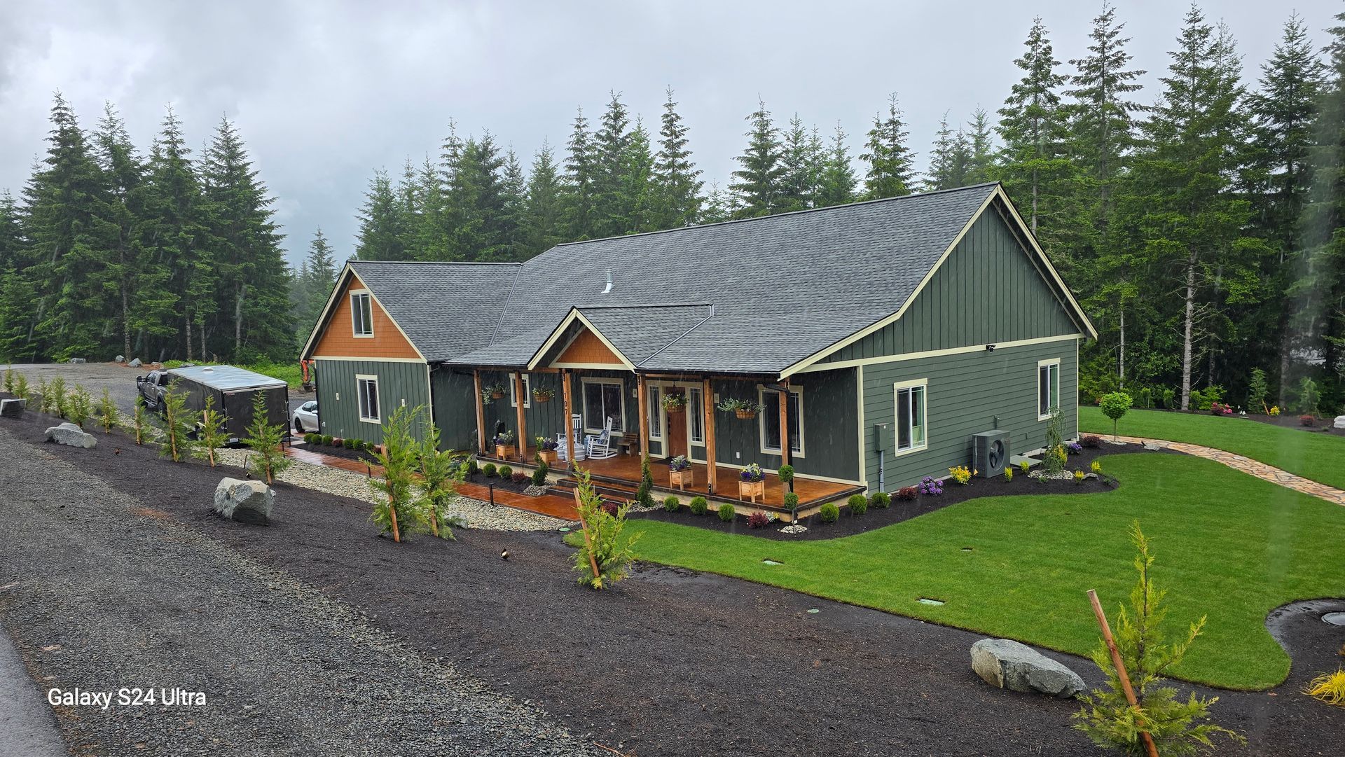 A large green house is surrounded by trees on a cloudy day.