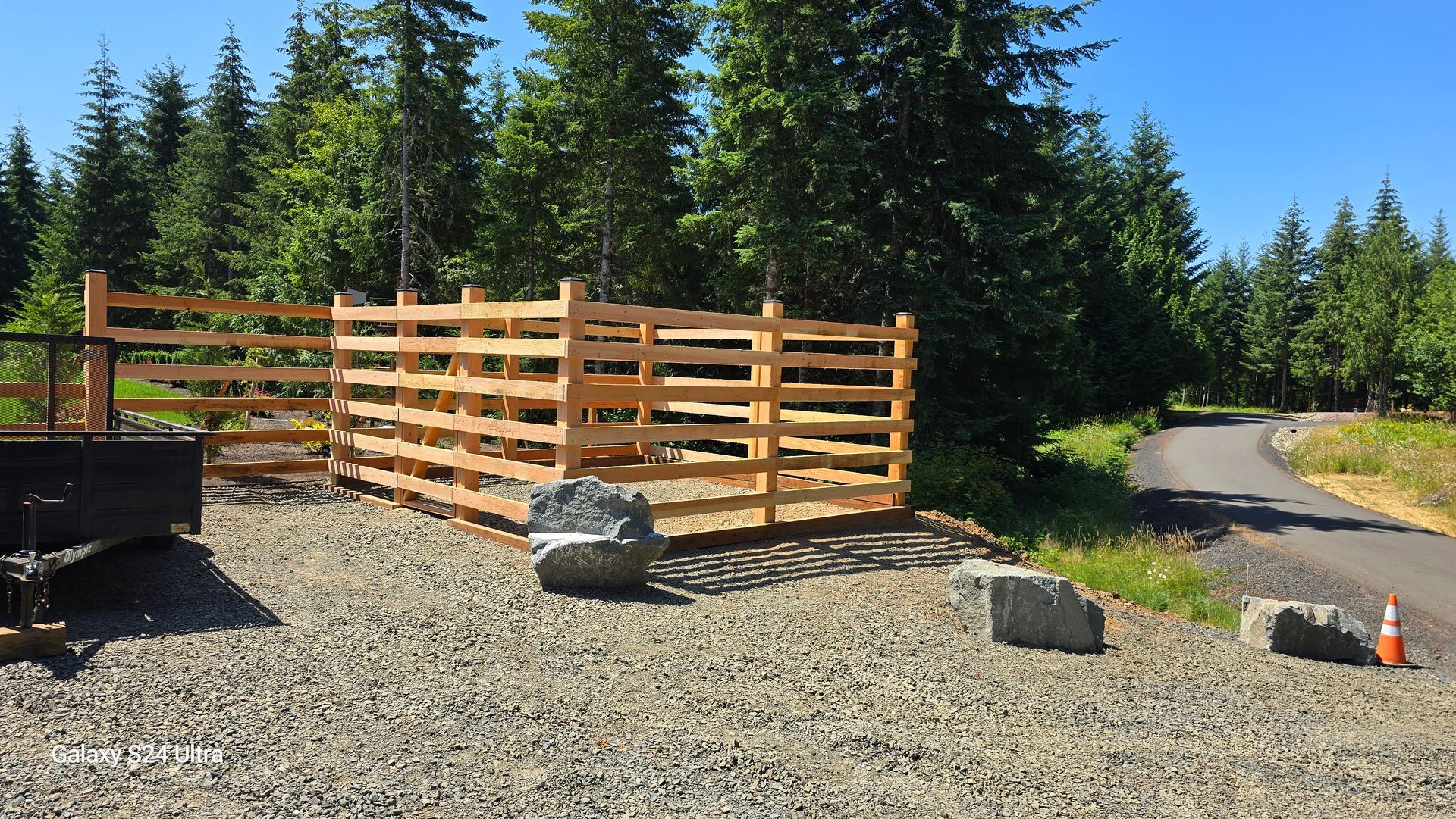 A wooden fence is in the middle of a gravel road
