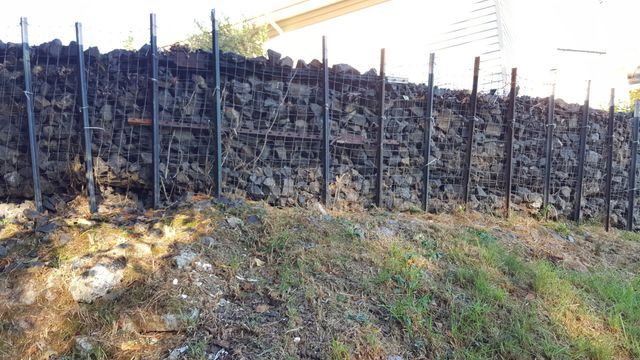 A large pile of rocks is sitting on top of a hill next to a fence.