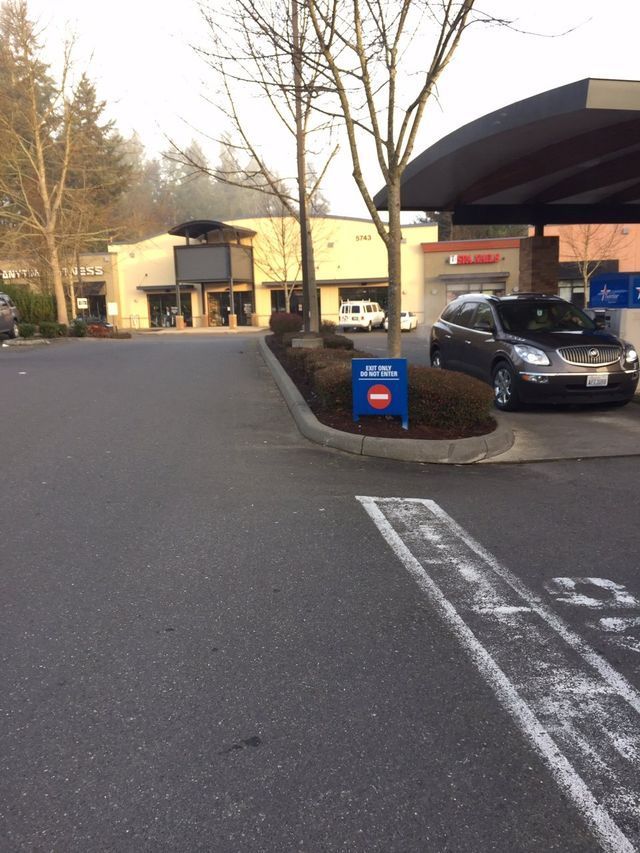 A car is parked in a parking lot next to a no parking sign