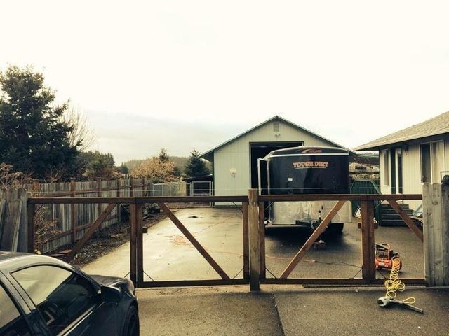 A black car is parked in front of a wooden gate