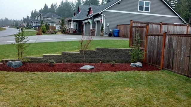 A yard with a fence and a house in the background.
