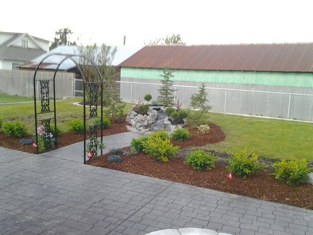 A garden with a walkway and a gazebo in front of a house.