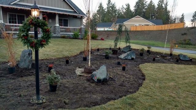 A christmas wreath is on a lamp post in front of a house.