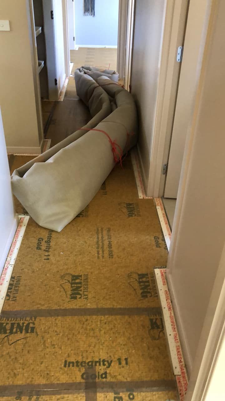 A roll of carpet is laying on the floor in a hallway.