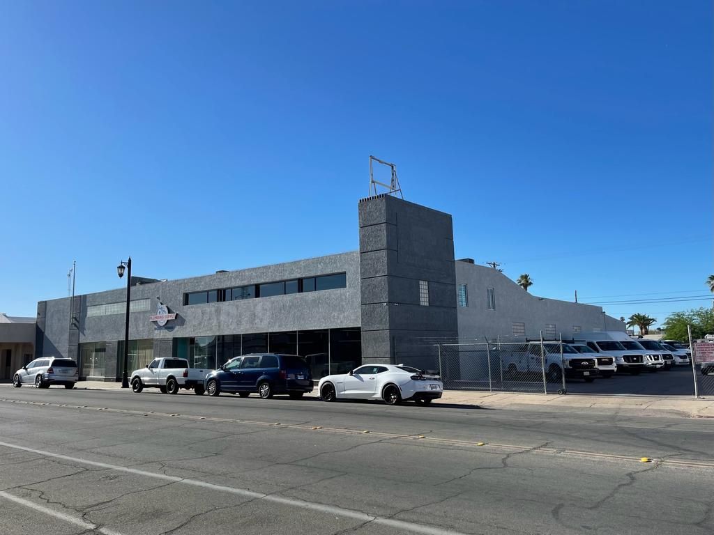 A row of cars are parked in front of a large building.