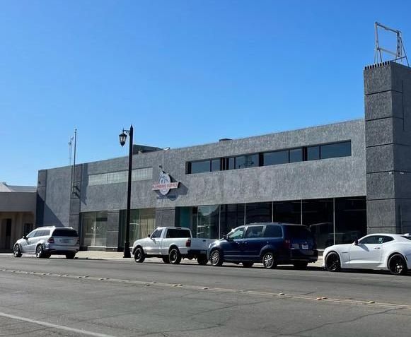 A row of cars are parked in front of a building.