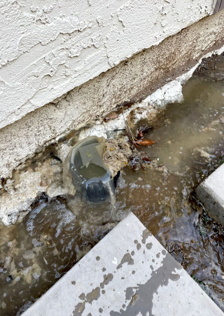 A close up of a drain with water coming out of it.