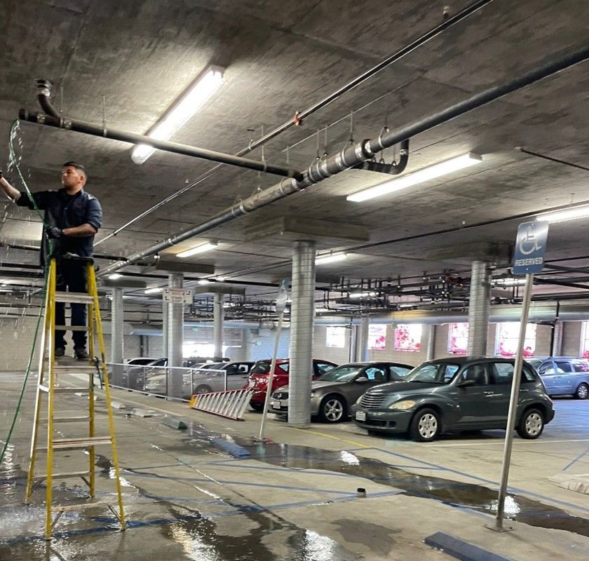 A man is standing on a ladder in a parking garage