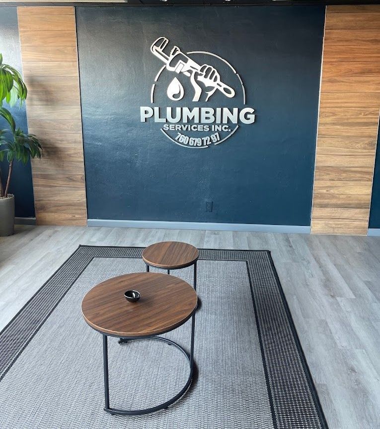 A room with two wooden tables and a plumbing logo on the wall.