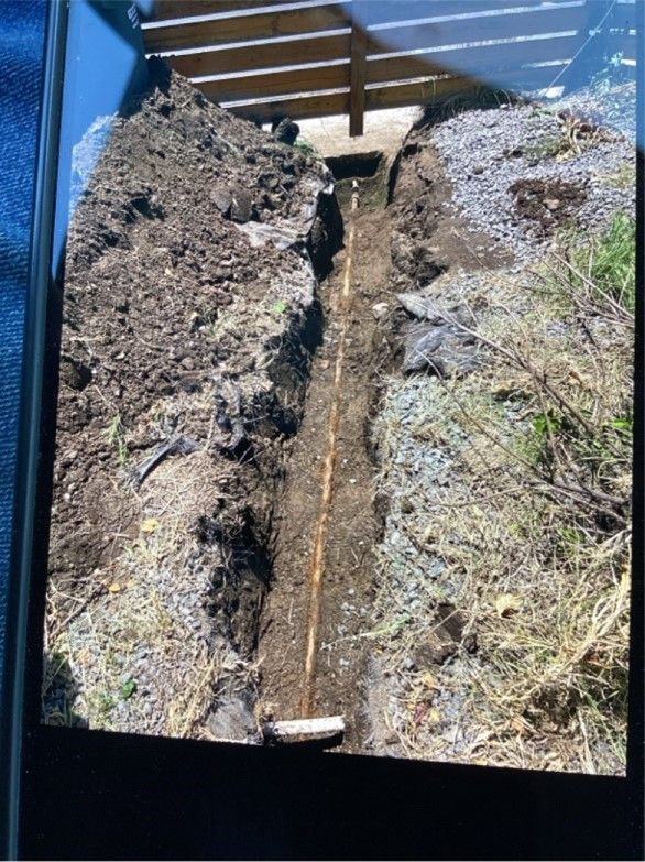 A picture of a hole in the ground with a water pipe.