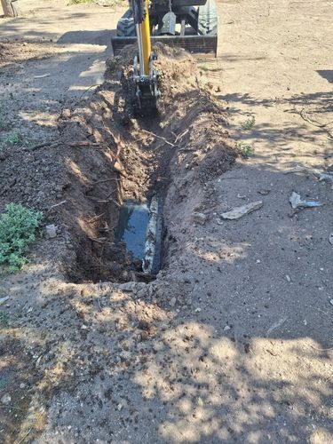 A small excavator is digging a hole in the ground.