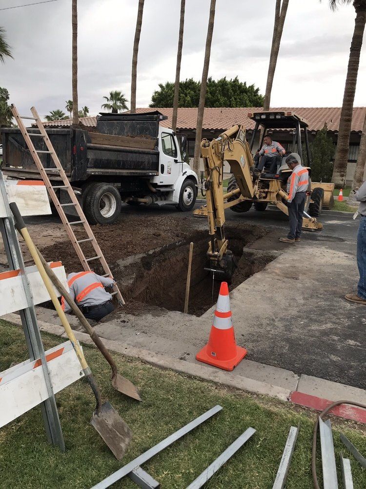 A man is digging a hole in the ground next to a dump truck.